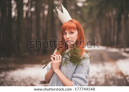 Hipster. Photo redheaded girl with a paper crown on his head. Young woman in forest.