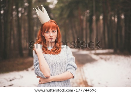 Hipster. Photo redheaded girl with a paper crown on his head. Young woman in forest.