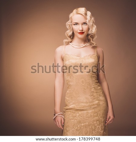 Vintage portrait of a girl in a gold dress. Blonde in studio.