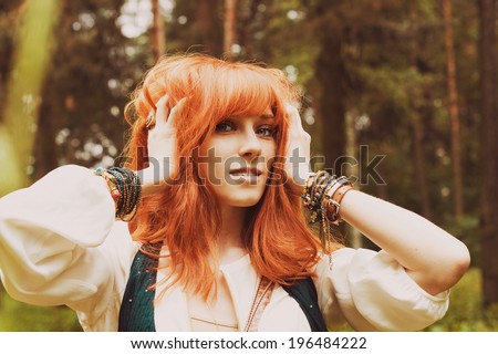 Portrait of romantic hippie woman smile in the woods. Young girl with hippie dress walking in the forest. Redhead girl in boho style.