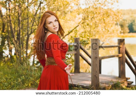 Redhead young girl in red dress enjoying the sunny freshness