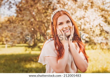 Beautiful smiling redhead woman with spring flowers outdoors