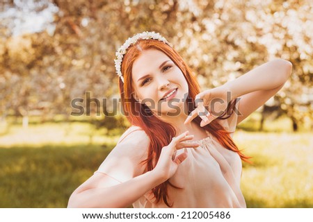 Beautiful smiling redhead woman with spring flowers outdoors