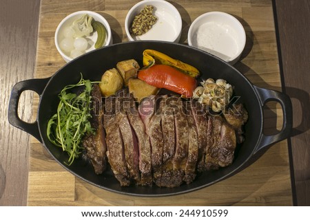 Roat medium-Rare fillet steak puts on a cocotte/dutch oven with side varied dish, onion, garlic, salt and mustard