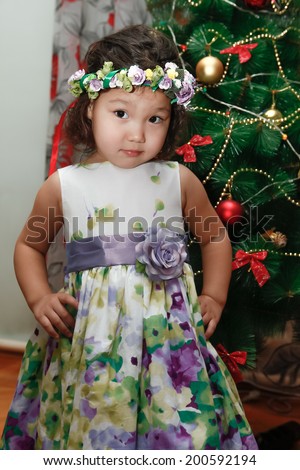 Kazakh girl in a fancy dress in front of Christmas tree