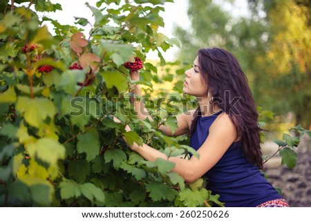beautiful woman looks at the bush viburnum berries. outdoors in the countryside
