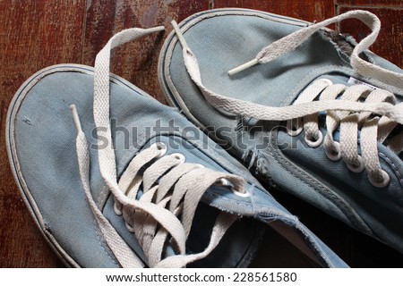 Old blue canvas shoe on wooden floor.