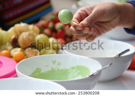 Woman making cape gooseberry in green tea chocolate glaze.