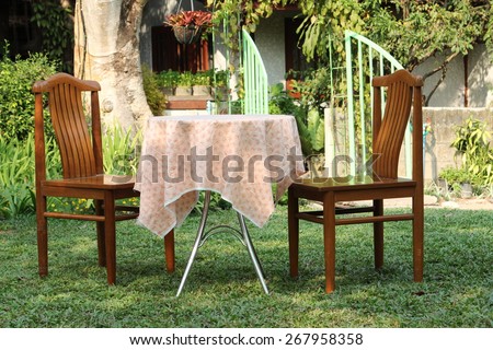 Garden furniture - Two vintage wooden chairs and steel table on green grass.