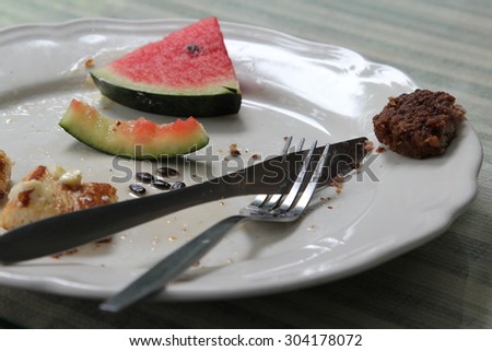 French toast with fresh red melon on white plate after eating.