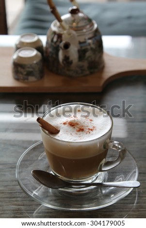 Hot cappuccino with frothed milk in clear cup on wooden table.