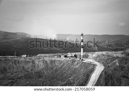 Black-and-white road, factory on top and hill