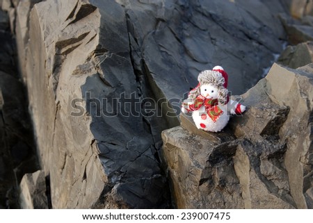 Snowman  in winter hat on the rocks in tropical place.