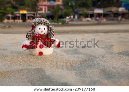 Snowman in winter hat on the tropical beach.