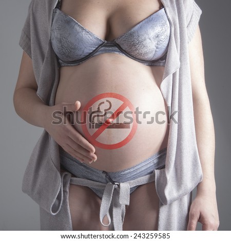 Pregnant woman with sign No smoking on her belly.