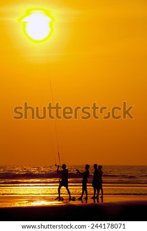 Group of men fishing. Sun reflected in orange waves.
