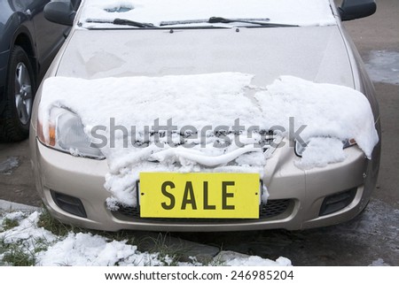 car covered with snow with a yellow label 'sale' instead of the number