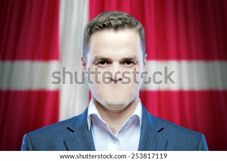 Symbol of censorship and freedom of speech: a young man without a mouth on a background of the national flag of Denmark