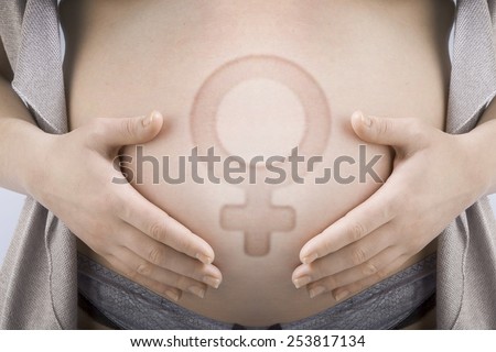 Pregnant woman supports her belly with a female gender sign - a girl