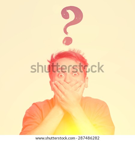 Young man with both hands closing mouth, with question sign above, isolated