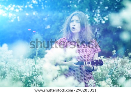 The girl in the early morning walks on the meadow with ukulele