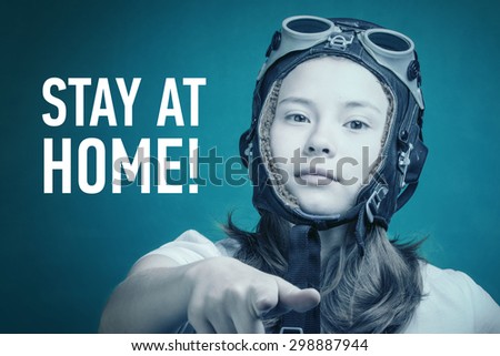 Girl in a flying helmet points finger with words Stay At Home!