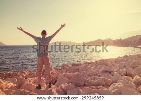Young man greets the sun on the beach
