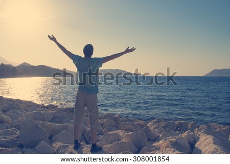 Young man greets the sun on the beach