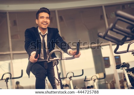 Handsome young man in a black suit, white shirt and tie training in the gym