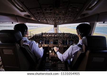 Two airliner pilots are flying the airplane towards the runway. Outside cockpit can see landing runway and environment. Inside cockpit can see pilots and all flight instrument and equipment.