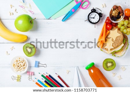 Back to school concept. Healthy lunch box and colorful stationery on white wooden table top view.