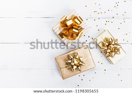 Heap of gift or present boxes and stars confetti on white wooden table top view. Flat lay composition for birthday, christmas or wedding.