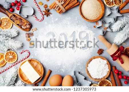 Bakery background with ingredients for cooking decorated with fir tree and new year 2019. Flour, brown sugar, eggs and spices top view.