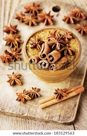 Cinnamon sticks, anise star and cane sugar in a wooden bowl on rustic board