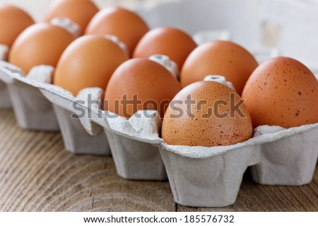 Chicken eggs in a carton box on a wooden rustic table