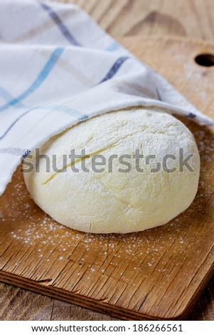 Dough ball covered with cloth on a wooden rustic kitchen board