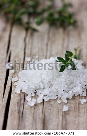 Sea salt with a fresh herbs thyme on a wooden rustic board