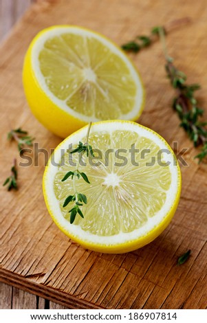 Lemon halves with herb thyme on a wooden cutting board