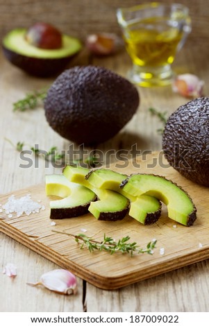 Avocado slices with olive oil, herb thyme, garlic and sea salt on a wooden cutting board