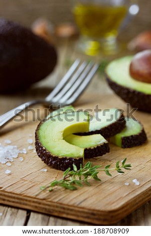 Avocado slices with olive oil, herb thyme, garlic and sea salt on a wooden board