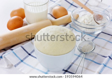 Dough with rolling pin on a linen napkin on the white wooden table
