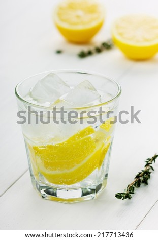 glass of water with lemons and ice cube on a white board