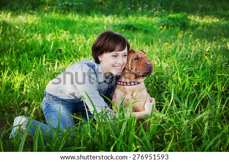 happy young woman playing with dog Shar Pei in the fresh green grass, true friends forever, people concept