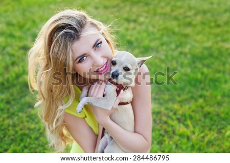 glamour happy smiling girl or gorgeous blonde woman holding cute chihuahua puppy dog on green lawn on the sunset, people pets concept, beautiful evening lights