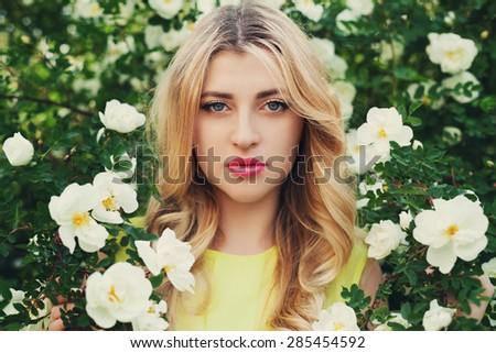 beautiful happy woman with long curly hair smells white roses flower outdoors, closeup portrait of sensual blonde amazing girl face, elegant lady in blossom garden, vintage toning