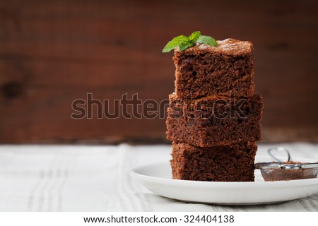 Brownie stack, closeup chocolate cake in plate on rustic wooden table