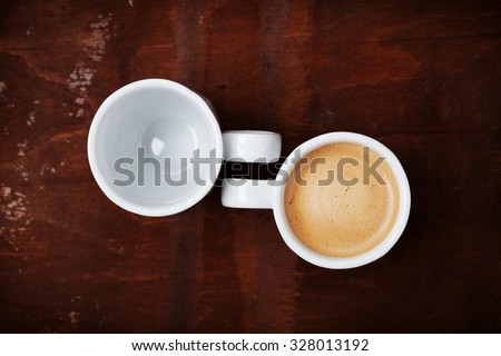 Empty and full cup of coffee on rustic wooden table, benefits and harms of coffee concept, top view