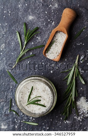 Sea salt scented herb rosemary on black stone background, vintage style, top view