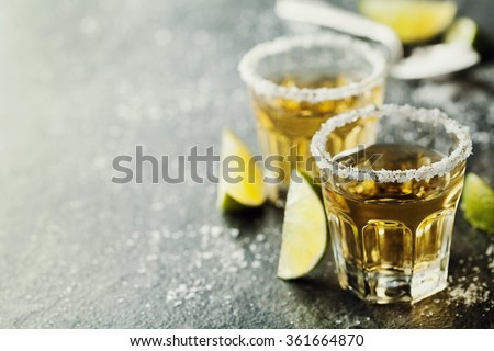 Tequila shot with lime and sea salt on black table, selective focus
