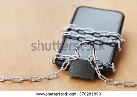 Smartphone tied chain with lock on wooden table, gadget and digital devices detox concept